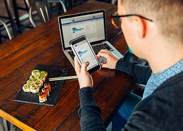 homme qui travaille sur son pc portable et qui regarde son téléphone mobile